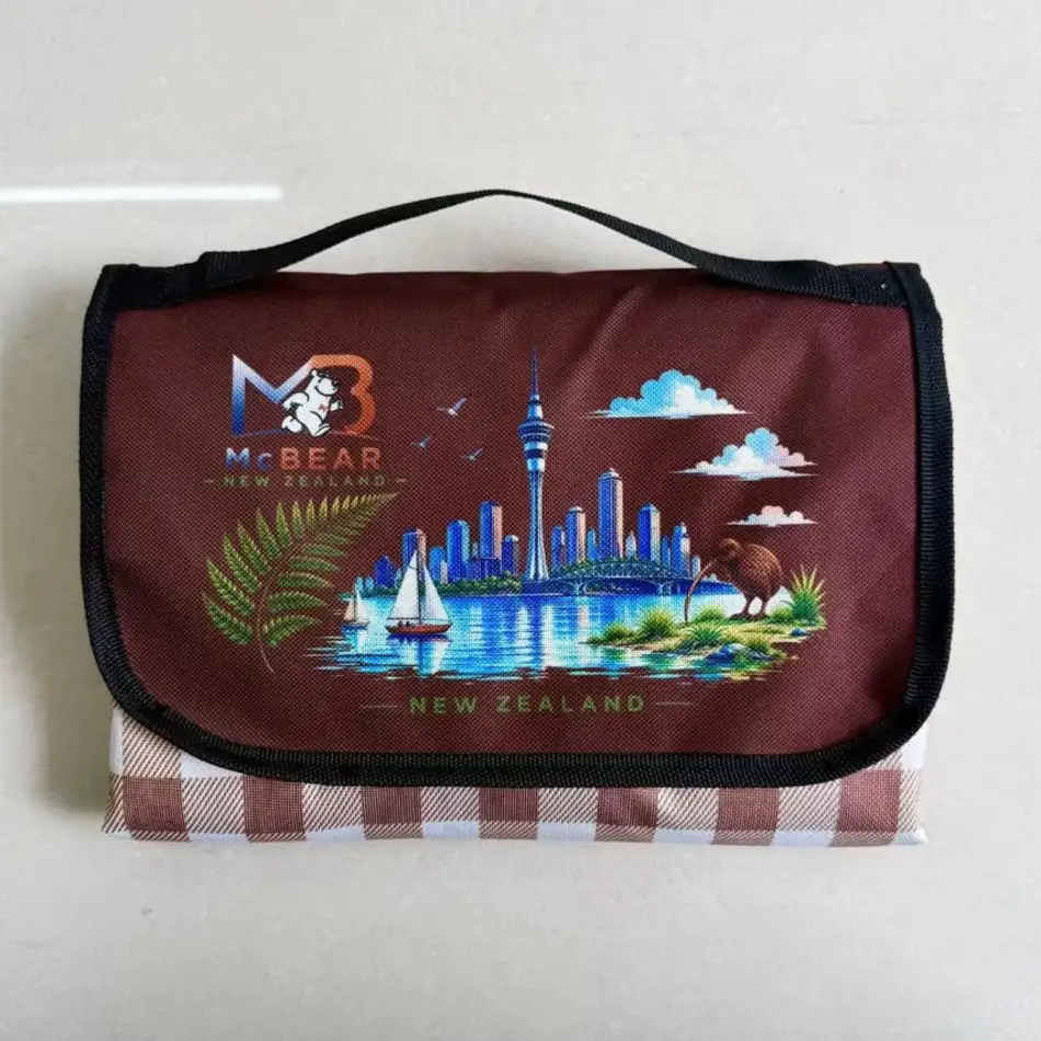 MC Bear NZ Picnic Mat folded into its brown carry bag with the New Zealand print